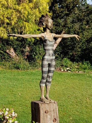 Sculpture with stretched out arms in a garden